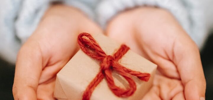 crop faceless woman showing small gift box on palms